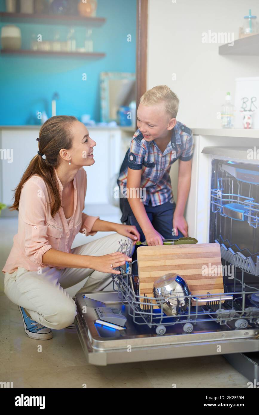 Einander zu helfen ist eine Freude. Aufnahme einer Mutter und eines Sohnes mit einer Spülmaschine. Stockfoto
