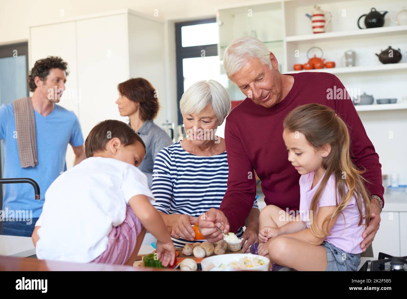 Das Essen ist das Herzstück dieser Familie. Aufnahme von Großeltern, die mit ihren Enkeln in einer Küche ein Abendessen zubereiten. Stockfoto
