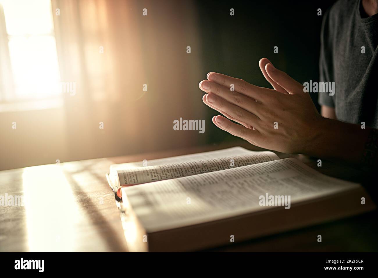 Seinen Tag richtig beginnen. Ausgeschnittene Aufnahme eines nicht identifizierbaren Mannes, der seine Hände im Gebet über eine offene Bibel klammert. Stockfoto