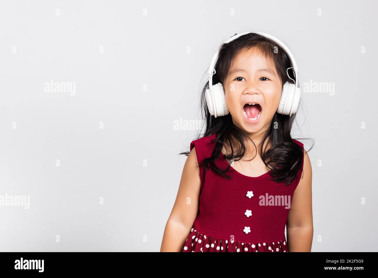 Kleines süßes Mädchen im Alter von 3-4 Jahren hört Musik mit kabellosen Kopfhörern Stockfoto