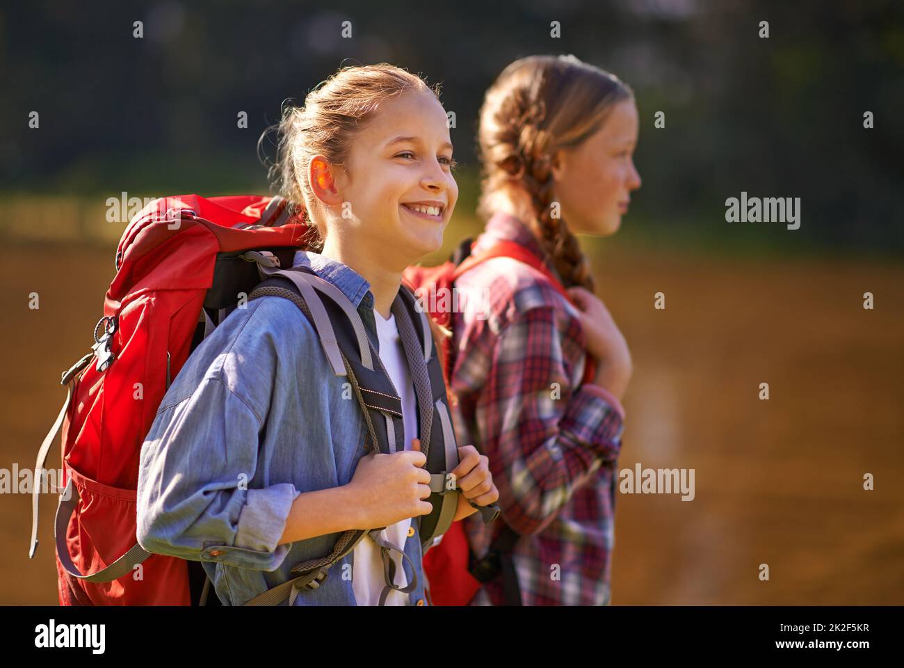 Sorglos in der Natur. Aufnahme von zwei jungen Mädchen in Rucksäcken, die zusammen spazieren gehen. Stockfoto