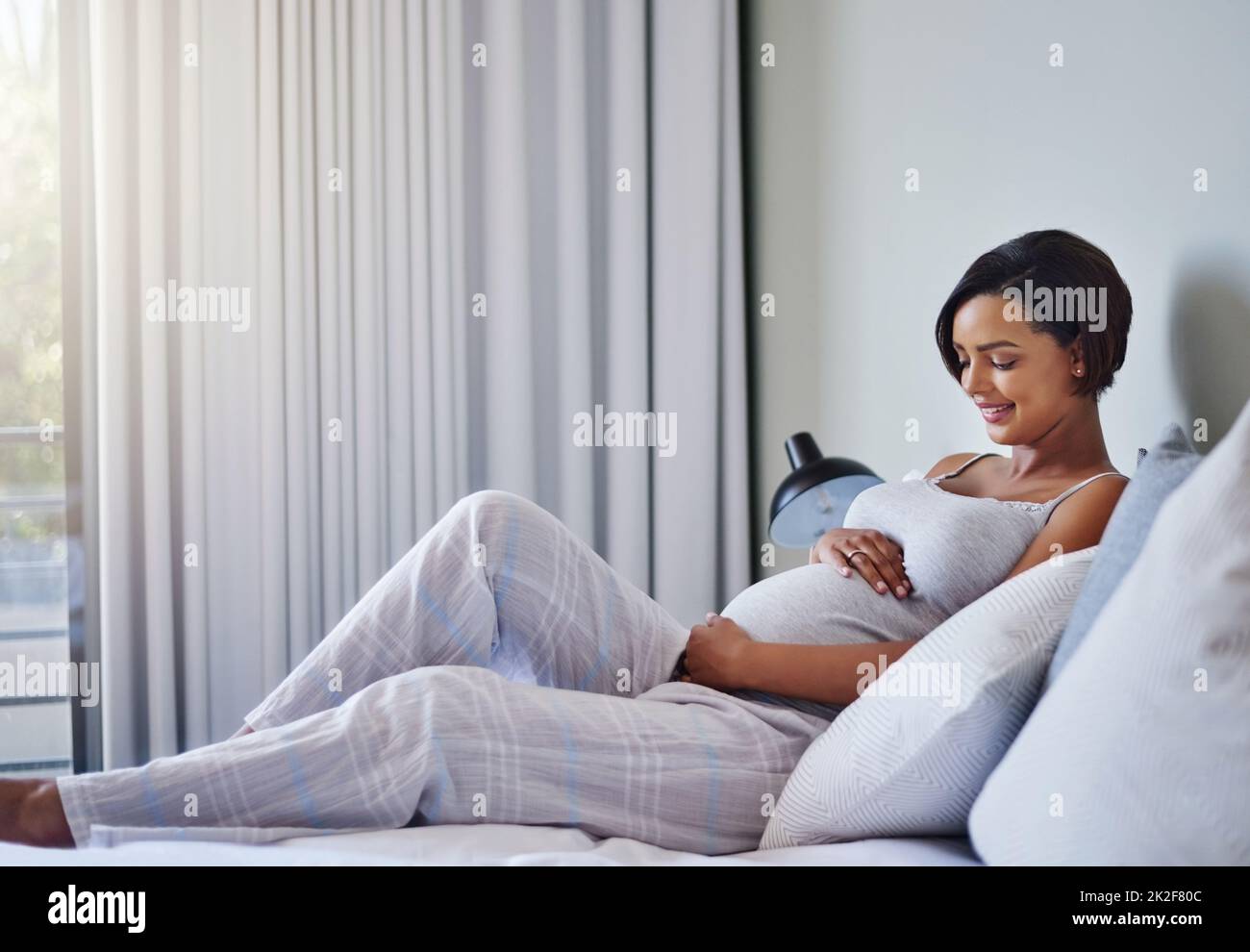 Der große Tag ist fast da. Aufnahme einer Schwangeren, die sich zu Hause auf dem Bett entspannt. Stockfoto