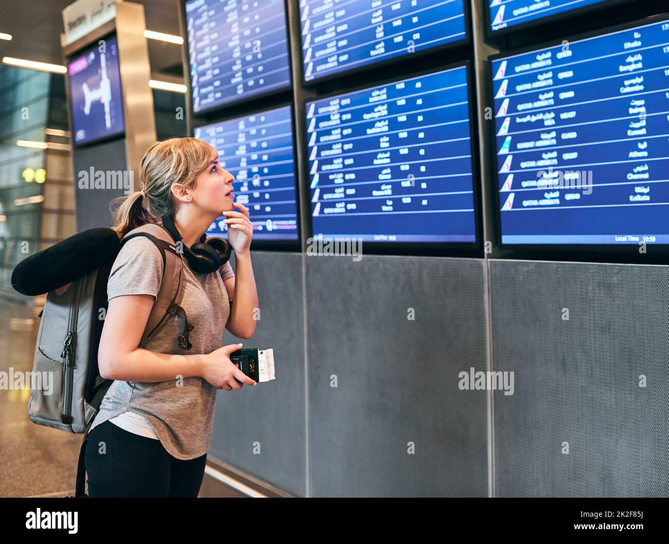 Wo ist mein Flug. Eine kurze Aufnahme einer attraktiven jungen Frau, die sich den Flugplan auf einem Flughafen ansieht. Stockfoto