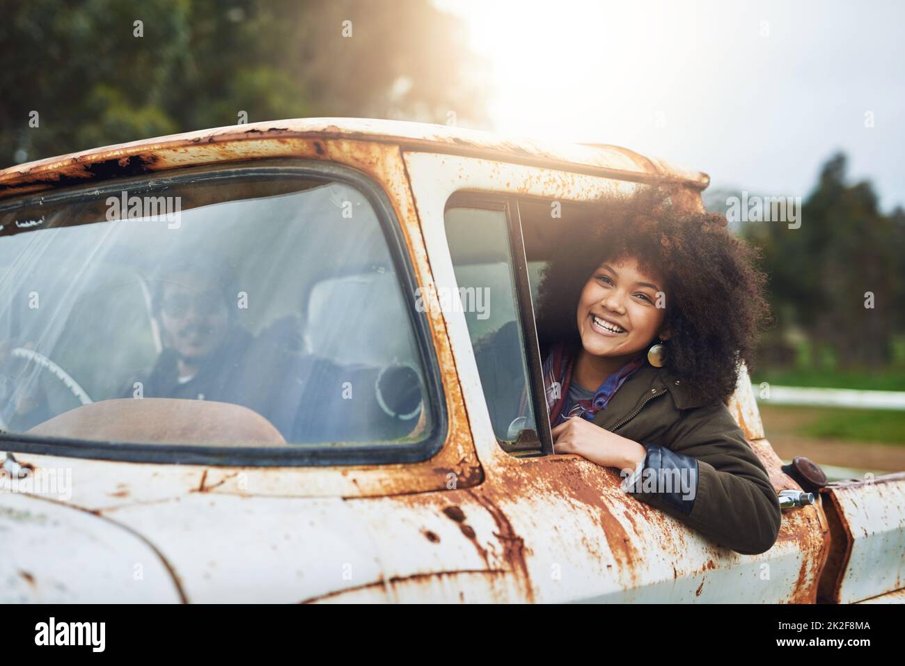 Also nie aufhören zu erkunden. Aufnahme einer glücklichen jungen Frau, die in einem rostigen alten Lastwagen sitzt. Stockfoto