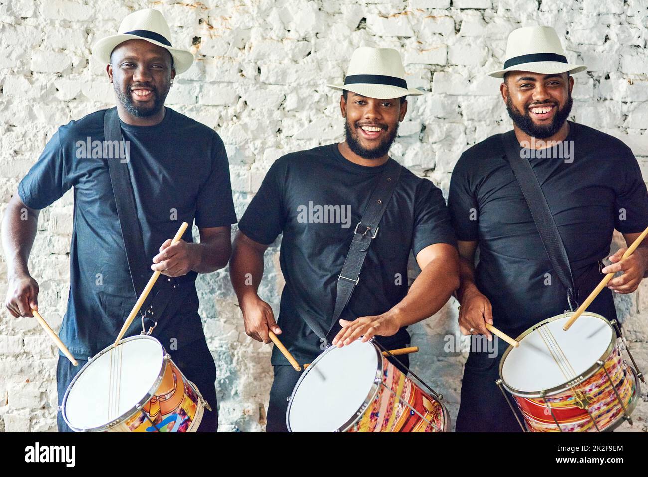 Hören Sie sich unsere Samba-Sounds an. Beschnittenes Porträt einer Gruppe von hübschen jungen männlichen Schlagzeugern, die an Karneval spielen. Stockfoto