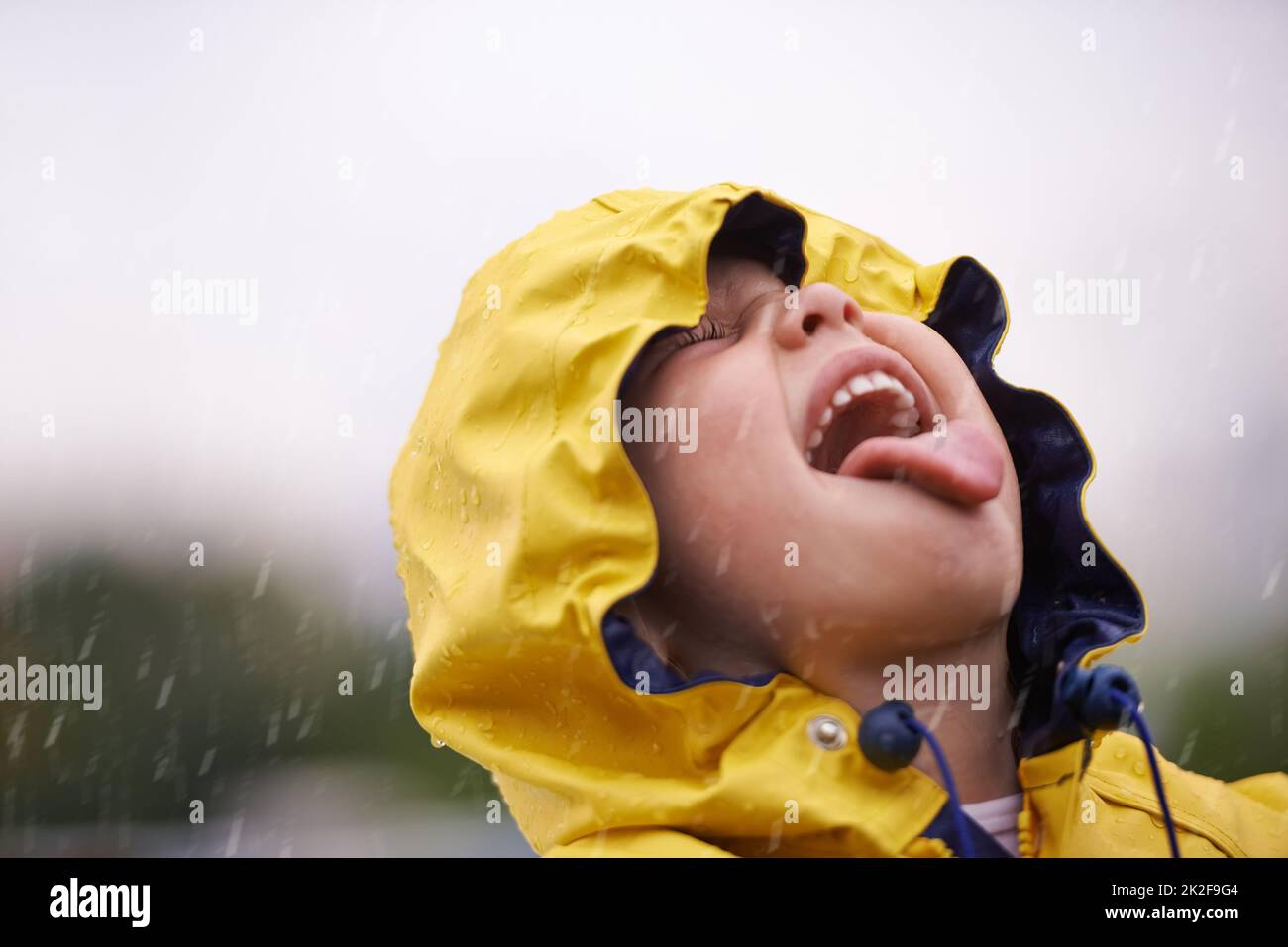 Reine Freude. Ein entzückendes kleines Mädchen, das draußen im Regen spielt. Stockfoto