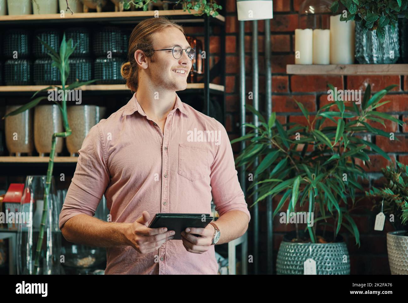 Mit einem Lächeln auf meinem Gesicht durch den Tag gehen. Ausgeschnittene Aufnahme eines hübschen jungen Geschäftsmanns, der allein in seinem Blumenladen steht und ein Tablet benutzt. Stockfoto