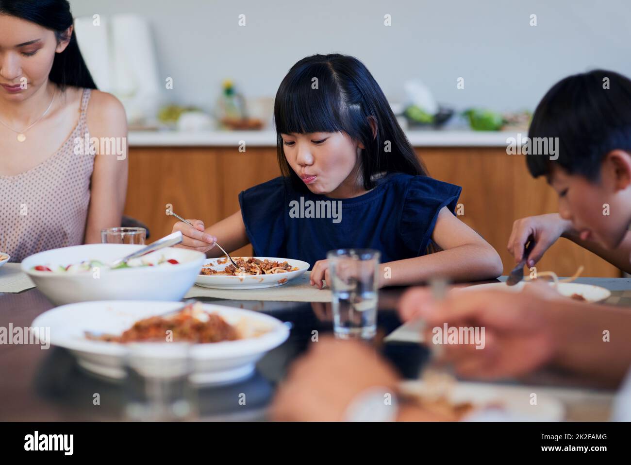 Ein Knaller von Yumminess. Aufnahme von zwei kleinen Kindern, die mit ihrer Mutter zu Hause essen. Stockfoto