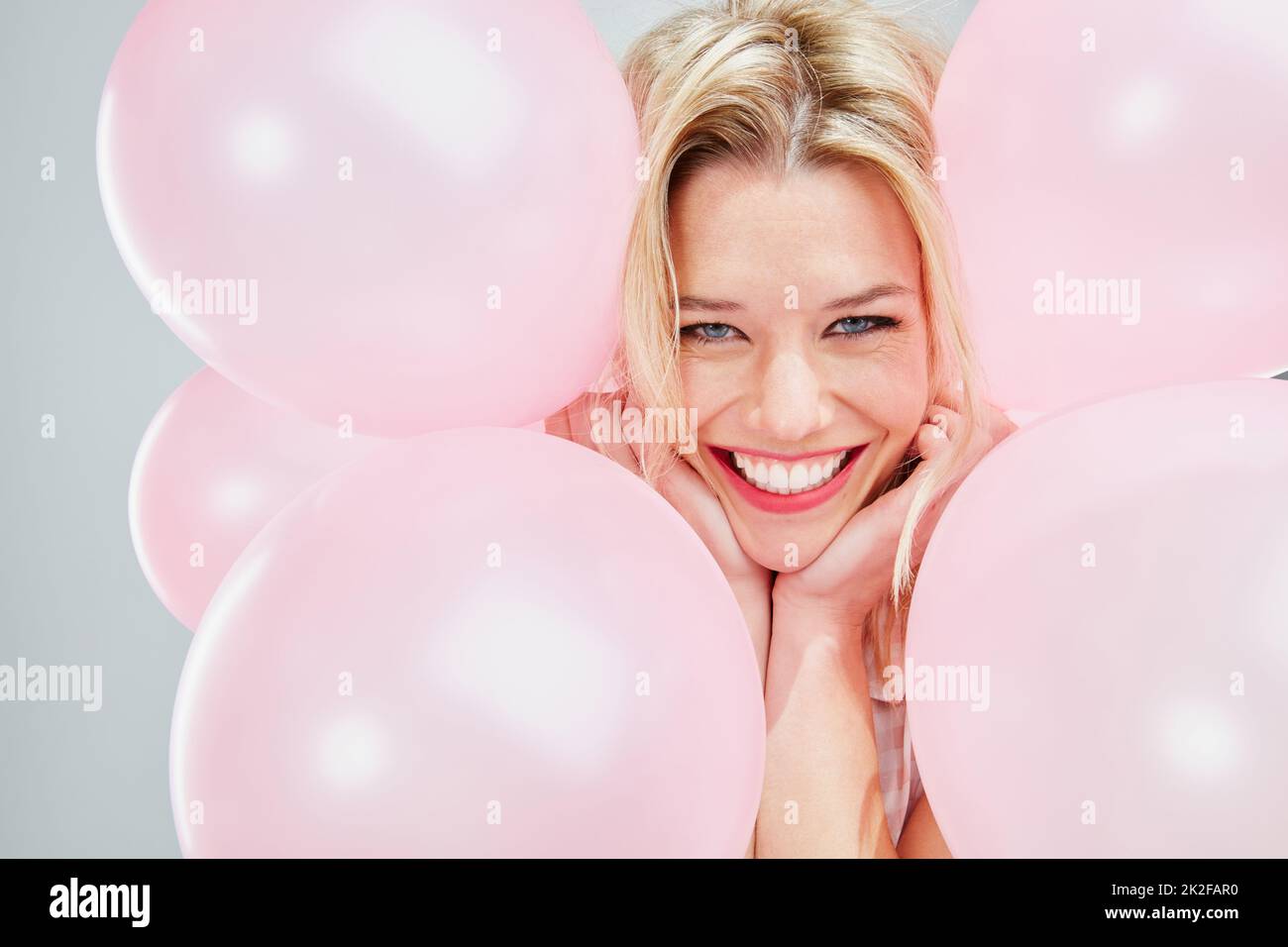 Ich weiß nicht, warum, aber ich bin so glücklich. Kurzer Schuss einer schönen jungen Frau, die mit rosa Luftballons posiert. Stockfoto