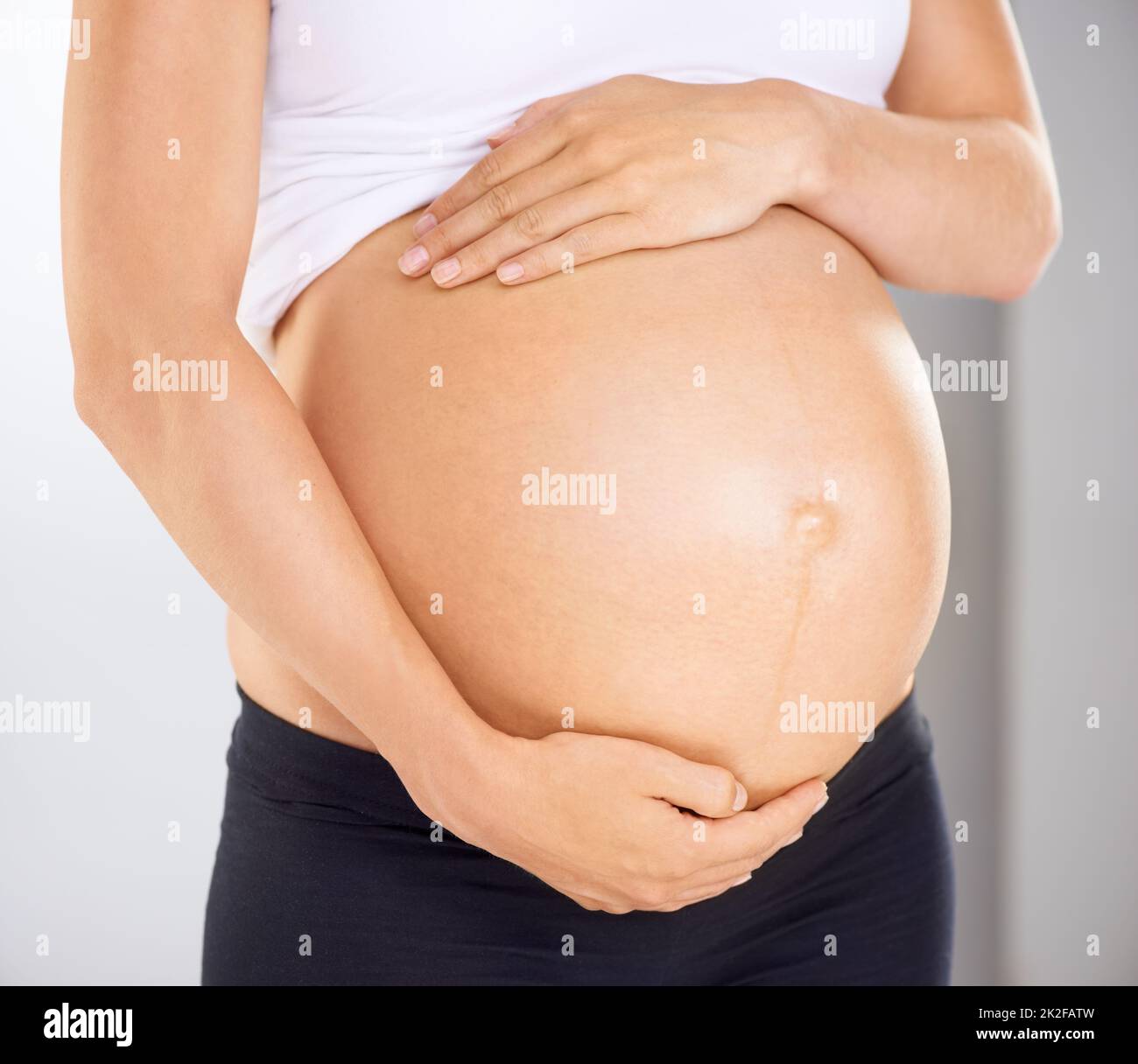 Ich liebe dich bereits. Zugeschnittenes Bild einer Schwangeren, die ihren Bauch liebevoll hält. Stockfoto