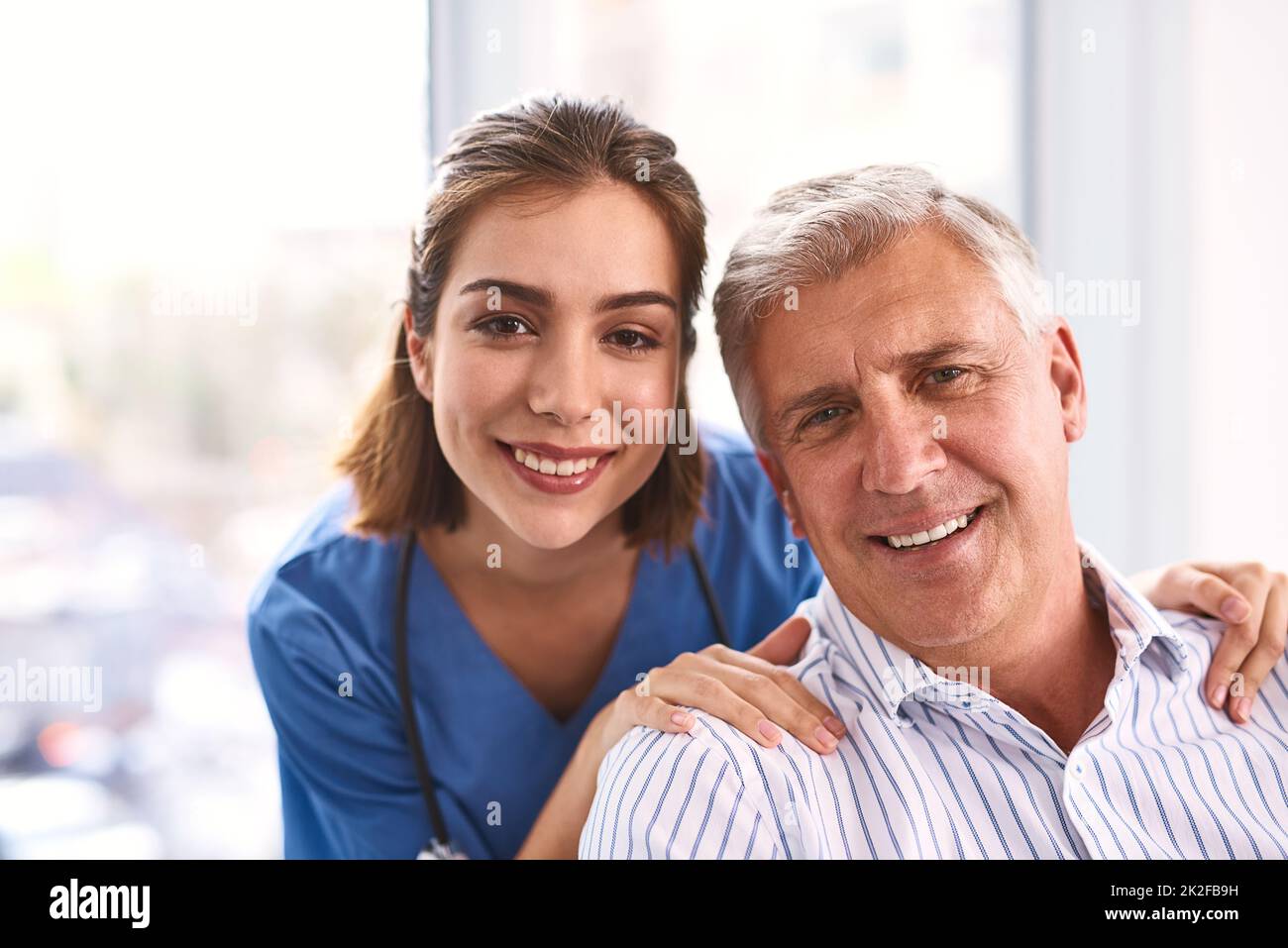 Patienten müssen sich nie mehr Sorgen machen. Porträt eines fröhlichen jungen Arztes und eines reifen männlichen Patienten, der lächelt und in die Kamera schaut. Stockfoto