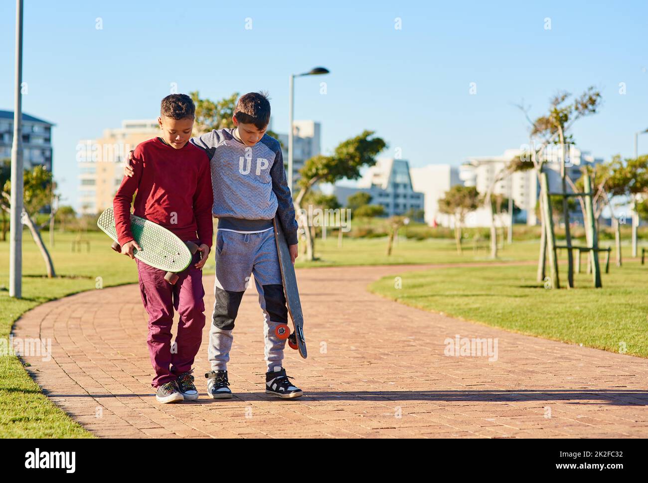 Sie teilen ein gemeinsames Hobby. Aufnahme von zwei jungen Brüdern, die mit ihren Skateboards im Park spazieren gehen. Stockfoto