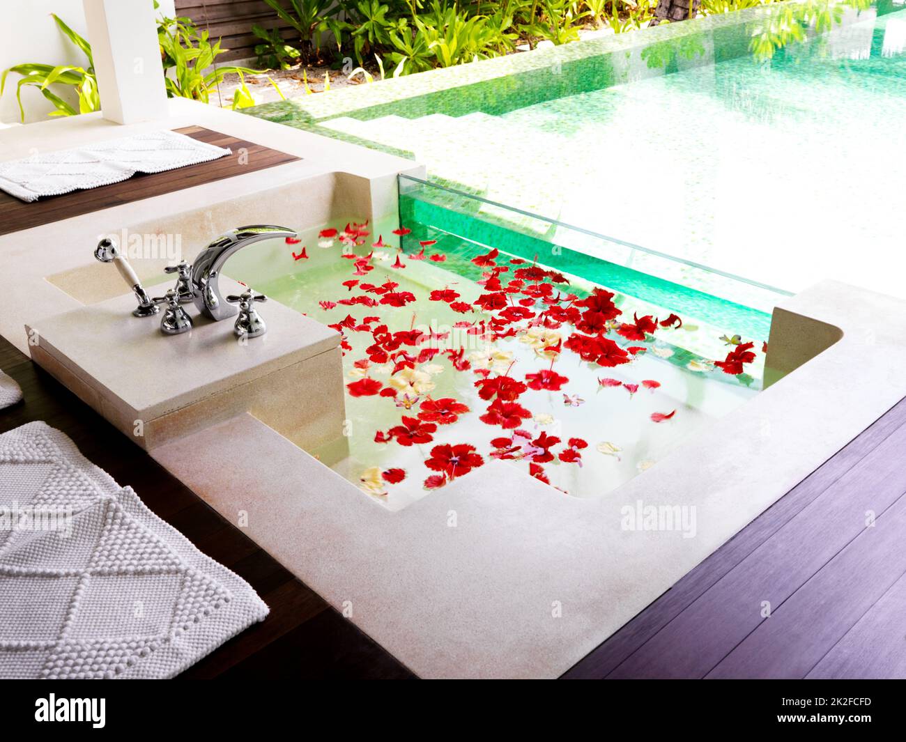 Bereit für Entspannung. Modernes Badezimmer mit Badewanne voller Blütenblätter in einem Spa-Resort. Stockfoto