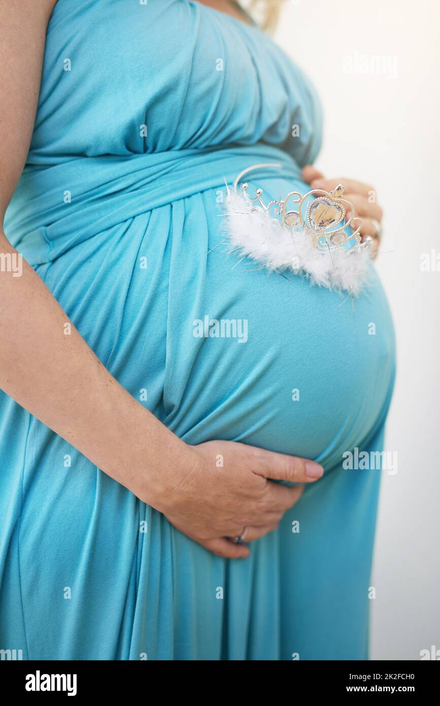 Mama liebt dich, kleine Prinzessin. Aufnahme einer nicht identifizierbaren Schwangeren, die eine Tiara an ihrem Bauch hält. Stockfoto