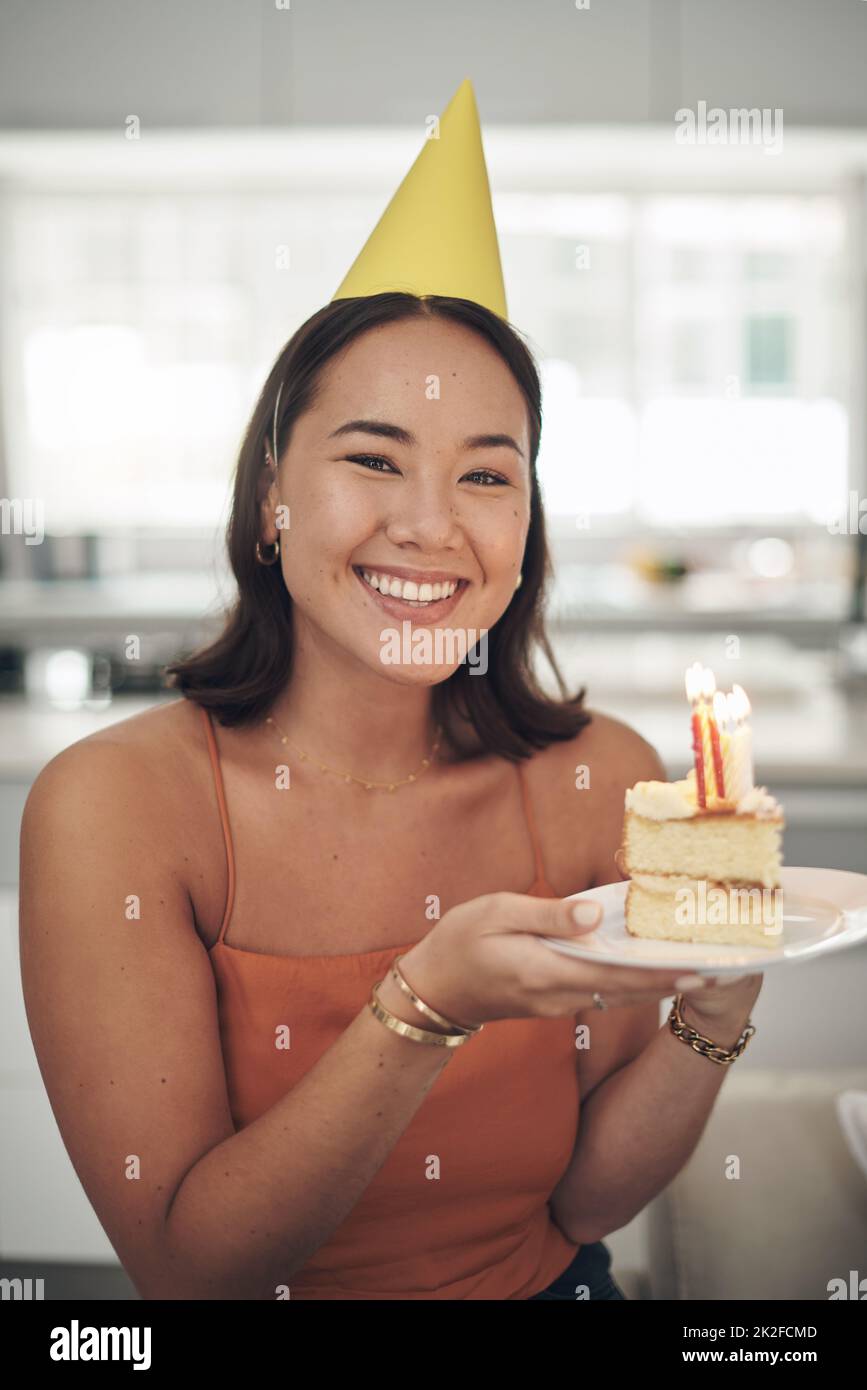 Wer mag Geburtstagskuchen nicht. Aufnahme einer jungen Frau, die zu Hause mit einem Stück Kuchen posiert. Stockfoto