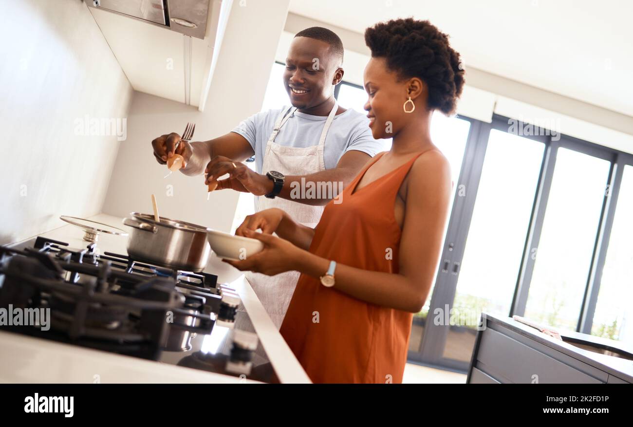 Alles, was Sie brauchen, ist Liebe und Essen. Aufnahme eines jungen Paares in der Küche, das zu Hause Essen zubereitet. Stockfoto