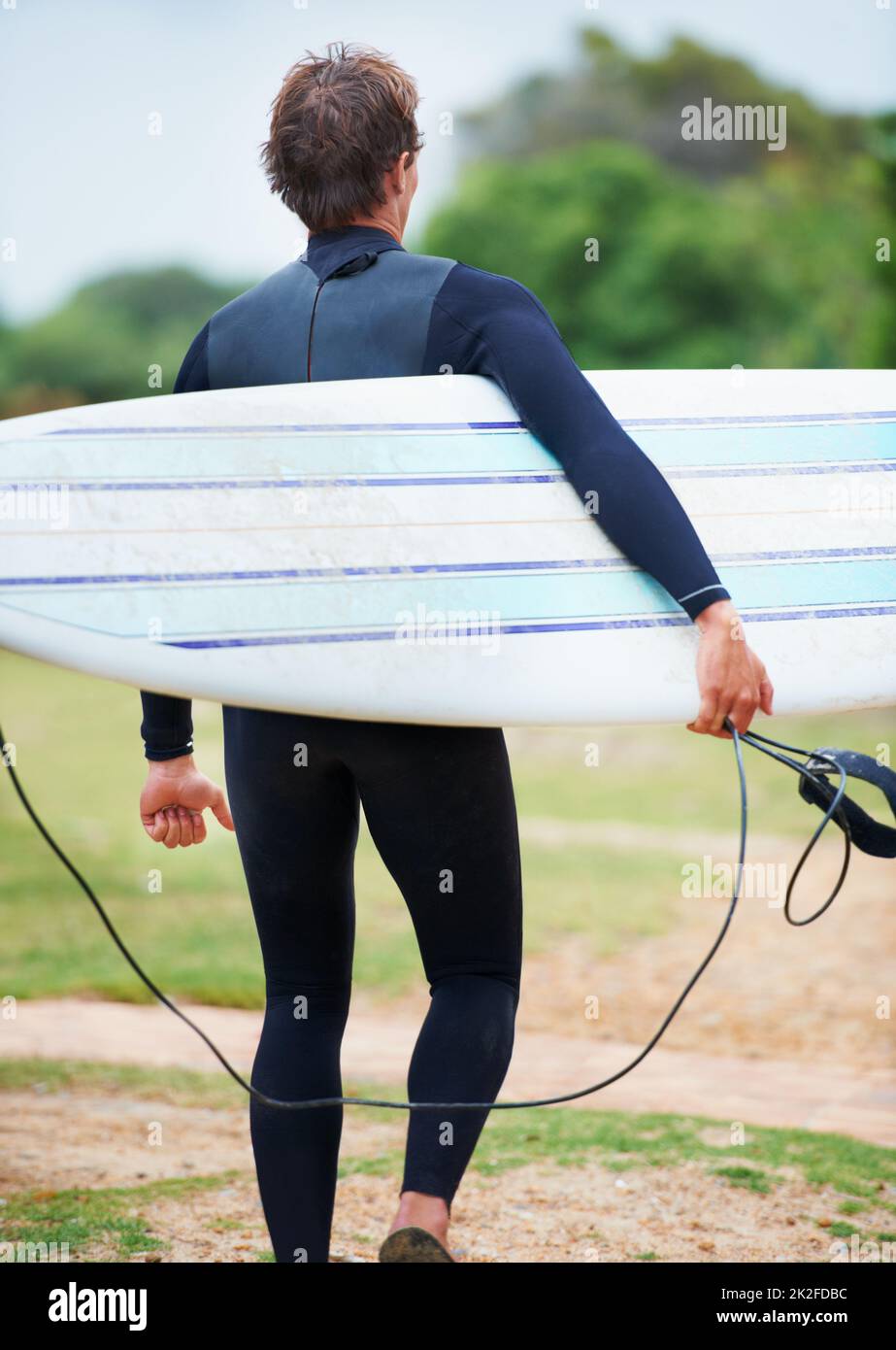Surfen ist ein Lebensstil. Ein Surfer, der sein Board auf dem Weg zum Strand trägt. Stockfoto