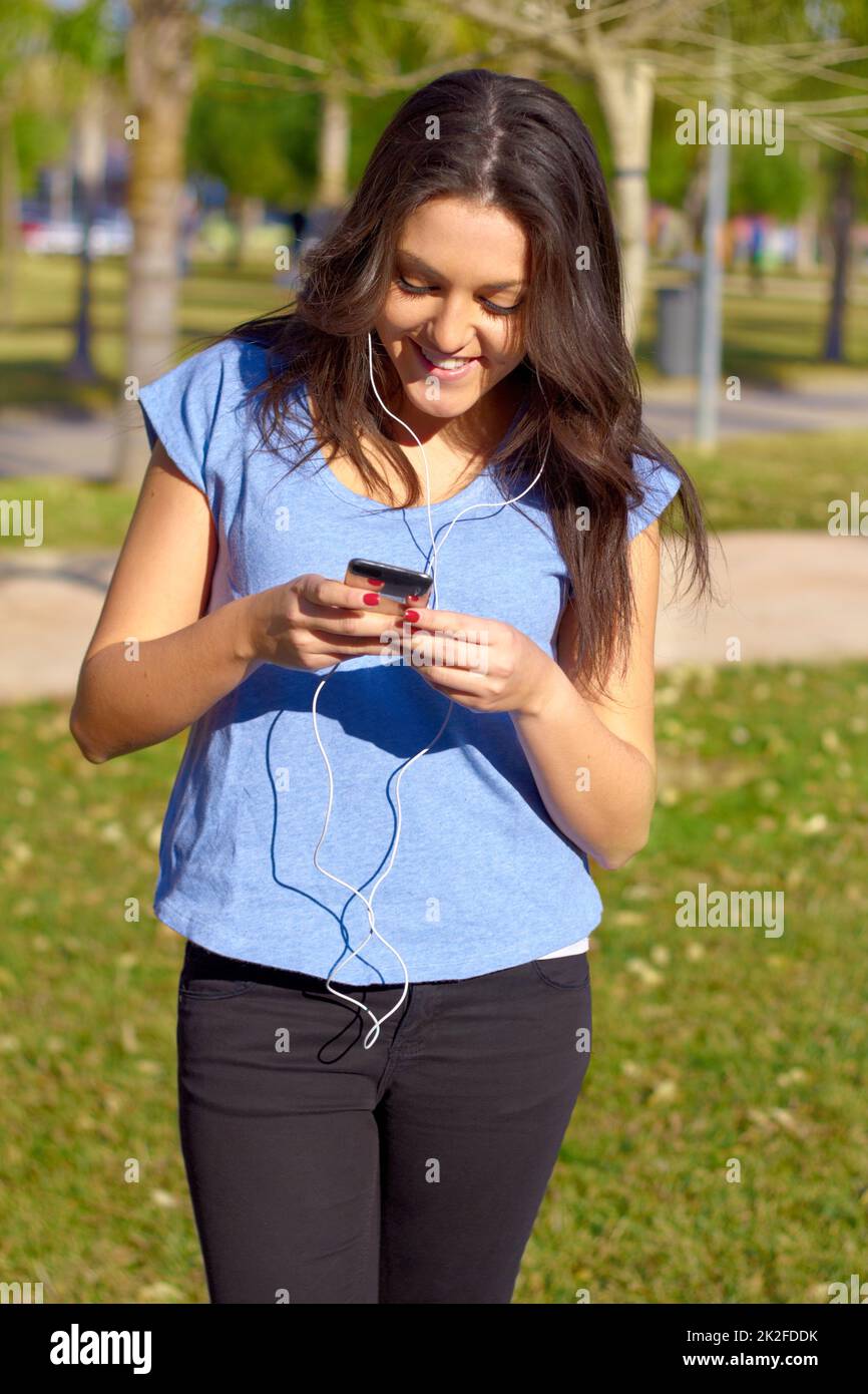 Musik, die zu ihrer Stimmung passt. Aufnahme einer attraktiven Frau, die im Park Musik hört. Stockfoto
