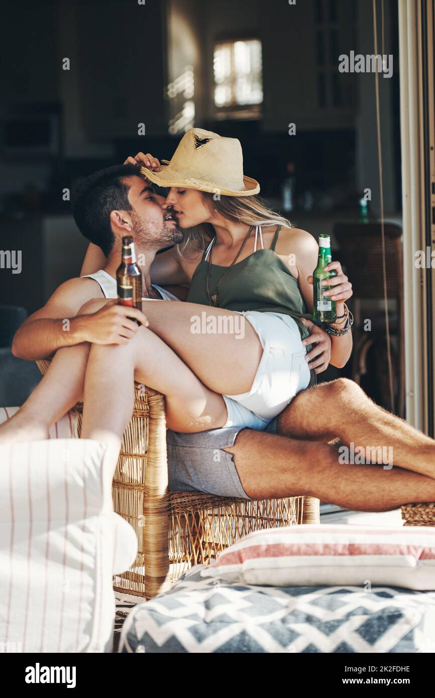 Sie sind jung und verliebt. Kurzer Schuss eines liebevollen jungen Paares, das sich küsst, während es auf der Terrasse ein paar Biere genießt. Stockfoto