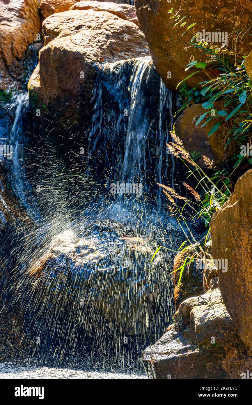 Kleiner Wasserfall, der zwischen Steinen scheint Stockfoto
