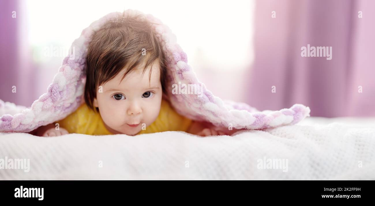 Niedliches kleines Baby, das unter einer rosa Decke liegt. Stockfoto