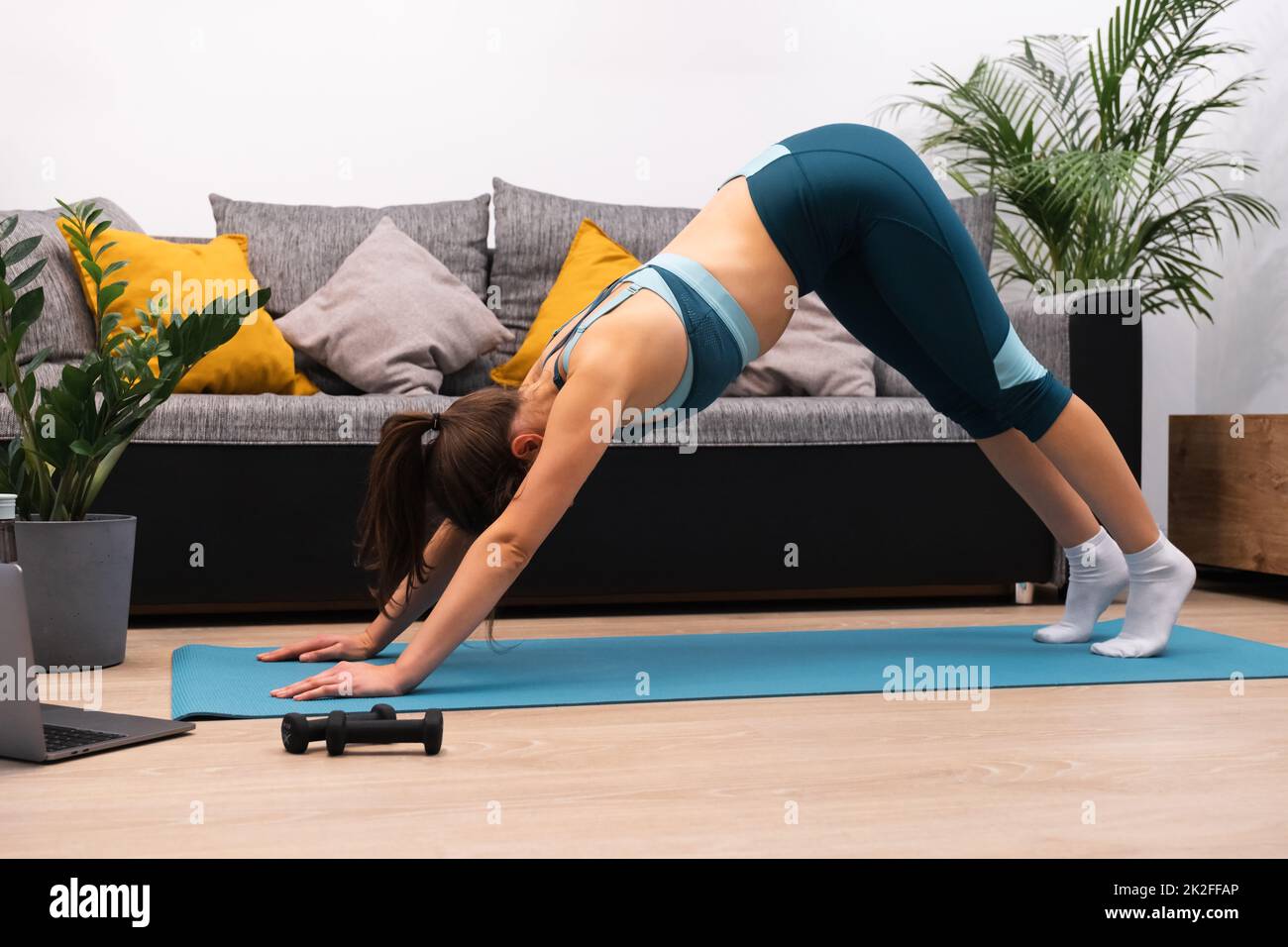 Schlanke junge Frau macht Stretching-Übung auf Gymnastikmatte zu Hause Stockfoto