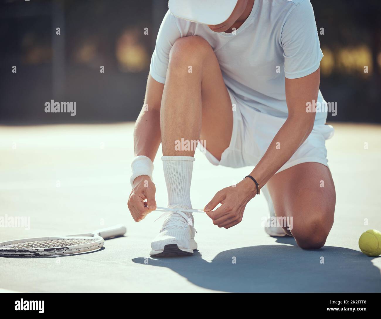 Sport, Tennis und ein Mann, der vor einem Spiel seine Schuhe auf einem Platz bindet. Sommer-Fitness, Sporttraining und gesunde Lebensweise mit Tennisball und Stockfoto