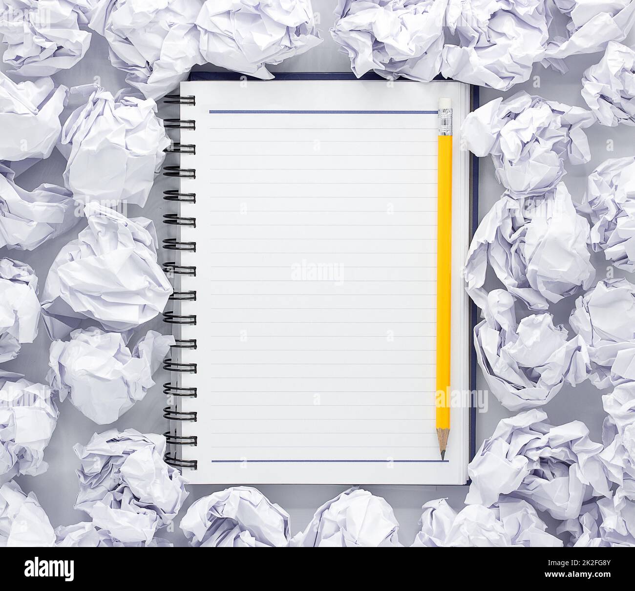 Weißes Notizblock auf weißem Hintergrund. Um die Notizblöcke liegt viel zerknittert Papier, Copy Space Stockfoto