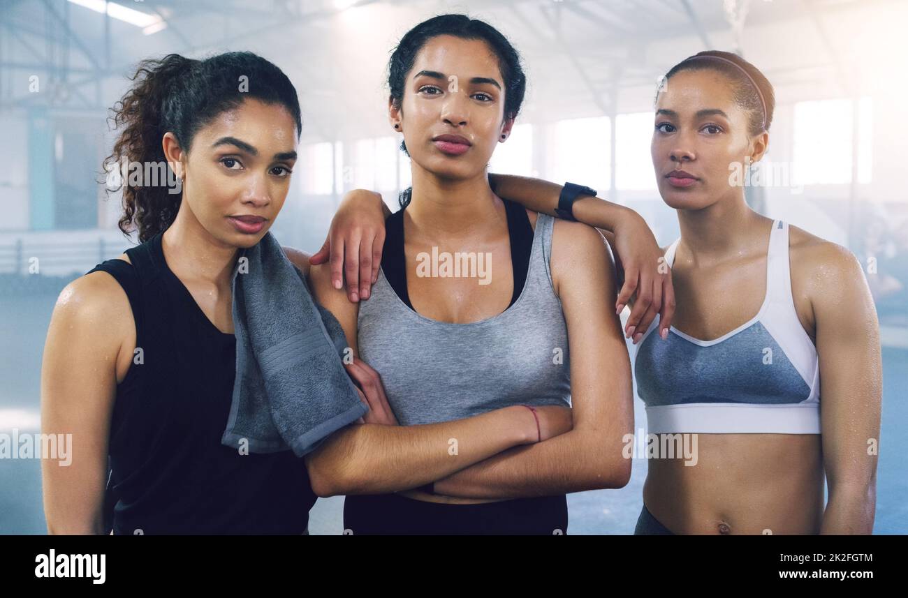 Gemeinsam stehen wir unbesiegt. Porträt von drei jungen Sportlerinnen, die in der Turnhalle stehen und posieren. Stockfoto
