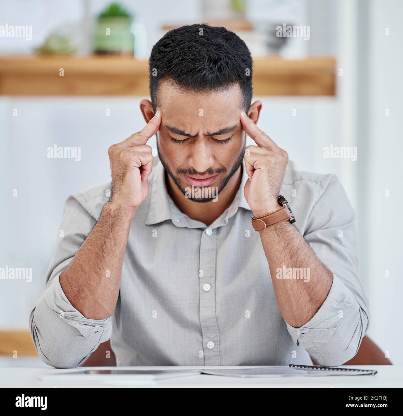 Mein Kopf fühlt sich an, als würde er explodieren. Aufnahme eines jungen Geschäftsmannes, der bei der Arbeit Kopfschmerzen hat. Stockfoto