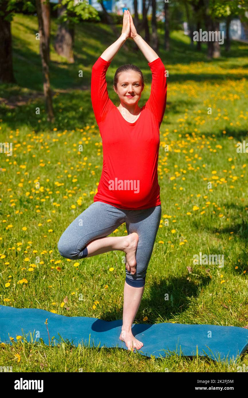 Schwanger Frau tun Asana vrikshasana im Freien Stockfoto