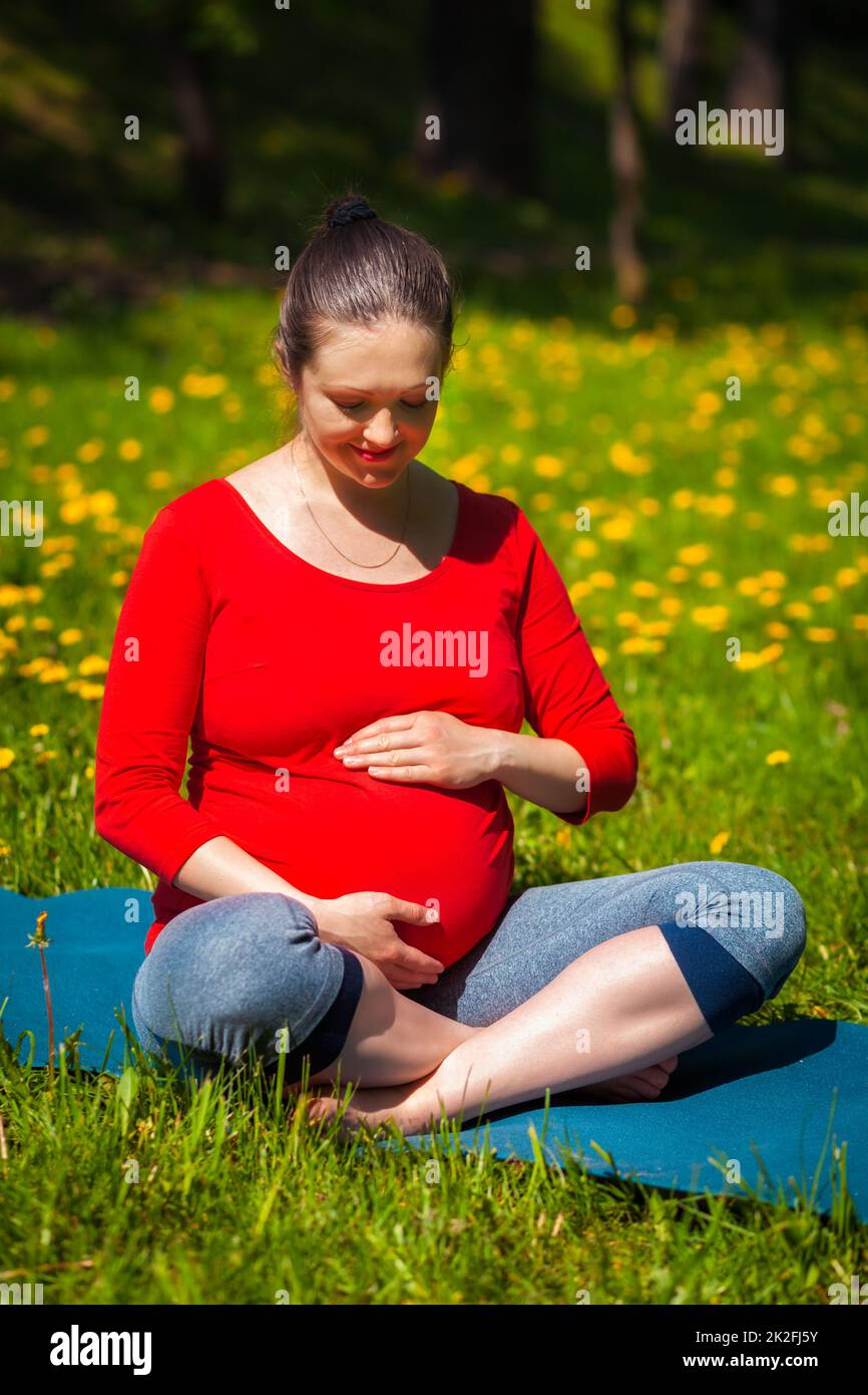 Schwangere, die im Freien Asana Sukhasana macht Stockfoto