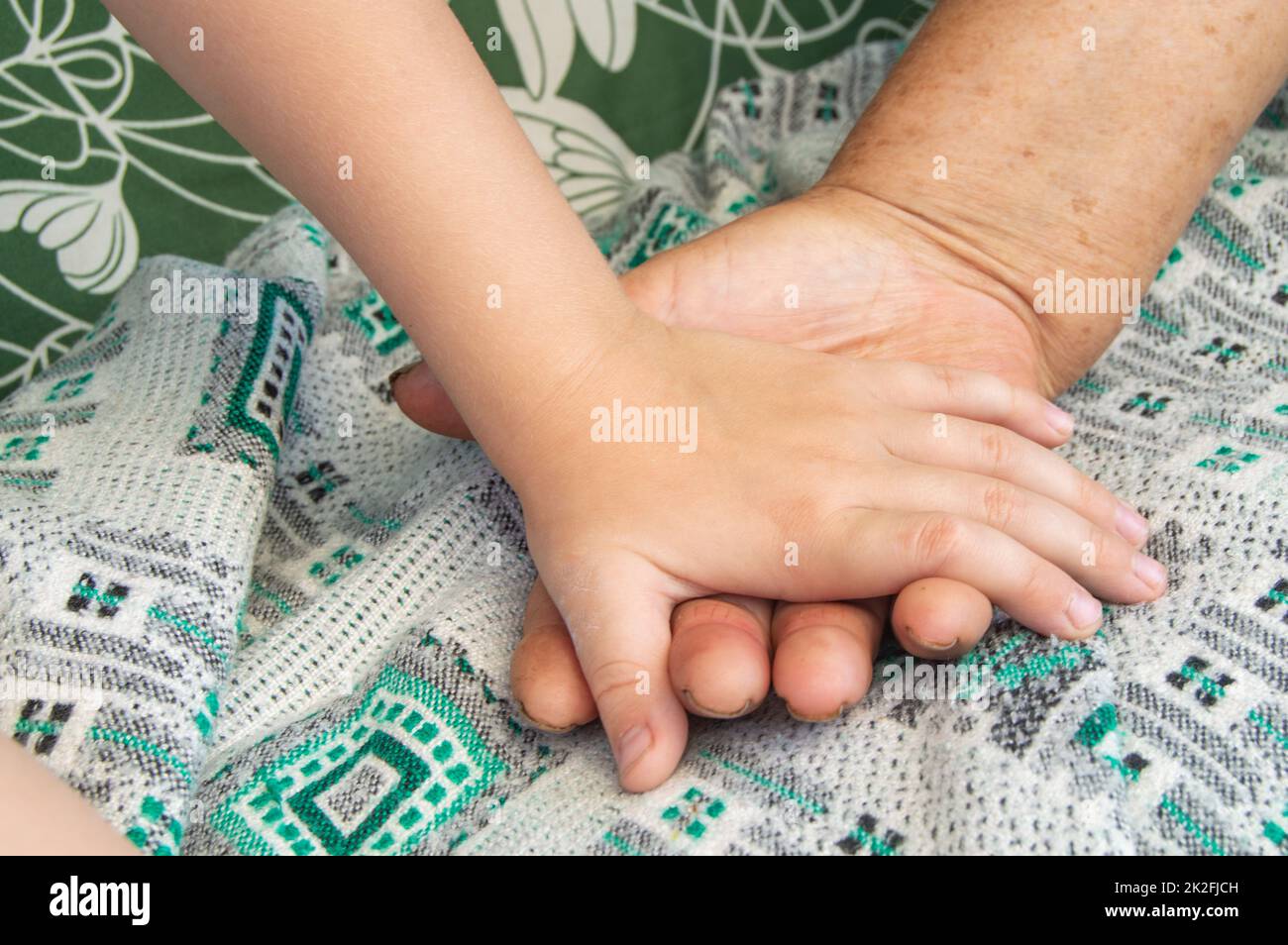 Nahaufnahme der Hände einer älteren Frau und eines Kleinkindes. Weichfokussierbild Stockfoto