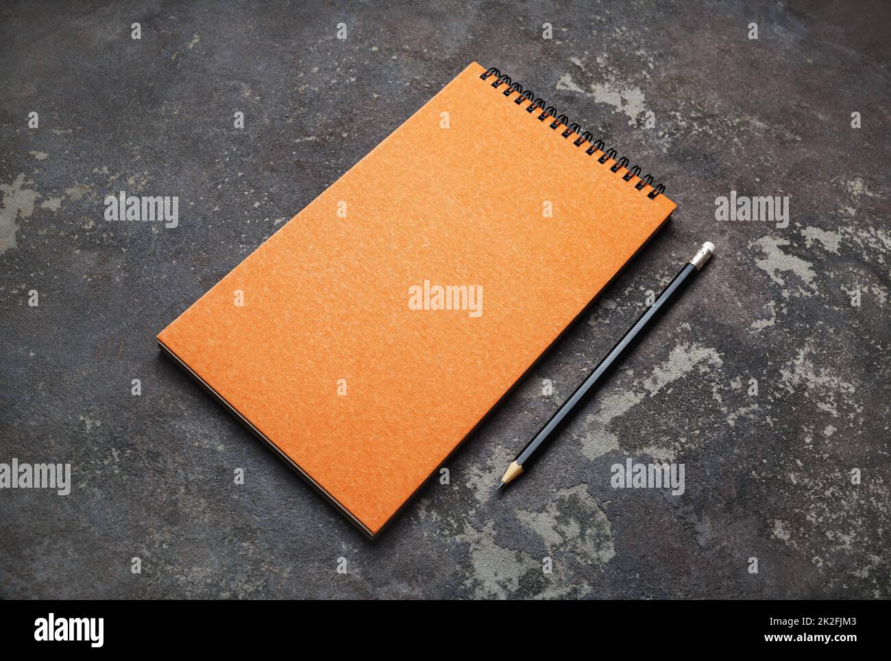 Orangefarbener Notizblock und Bleistift Stockfoto