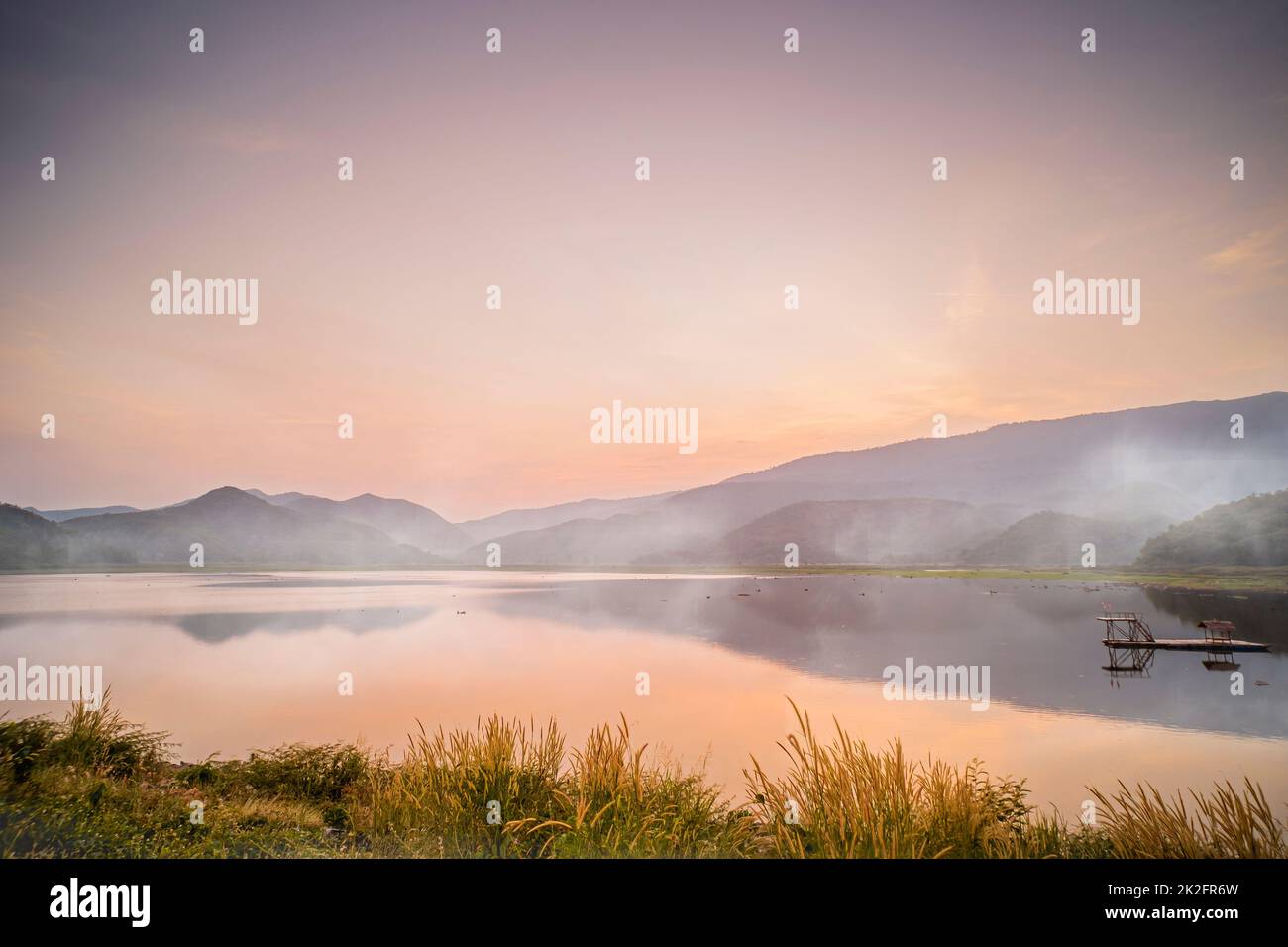 Idyllisch dramatischer Sonnenuntergang mit der Szene von Nebel über den Lake Mountains im Hintergrund am Khao Luang Reservoir. In Sukhothai Thailand Stockfoto