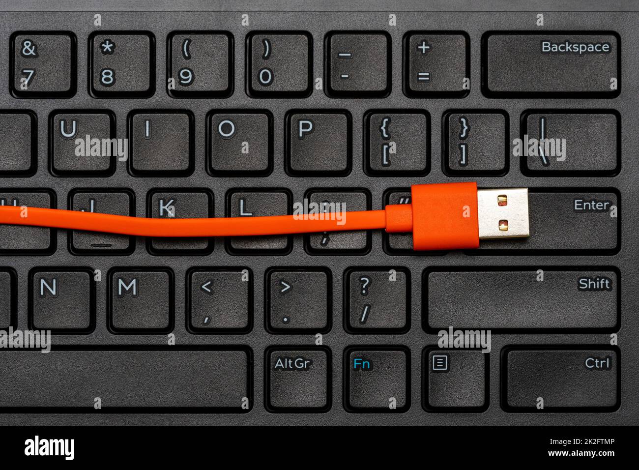 Computertastatur und orangefarbenes USB-Kabel Stockfoto