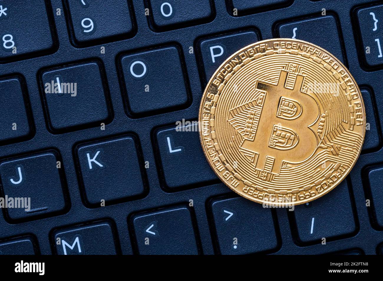 Ein goldenes Bitcoin auf dunkler Tastatur des Computers Stockfoto