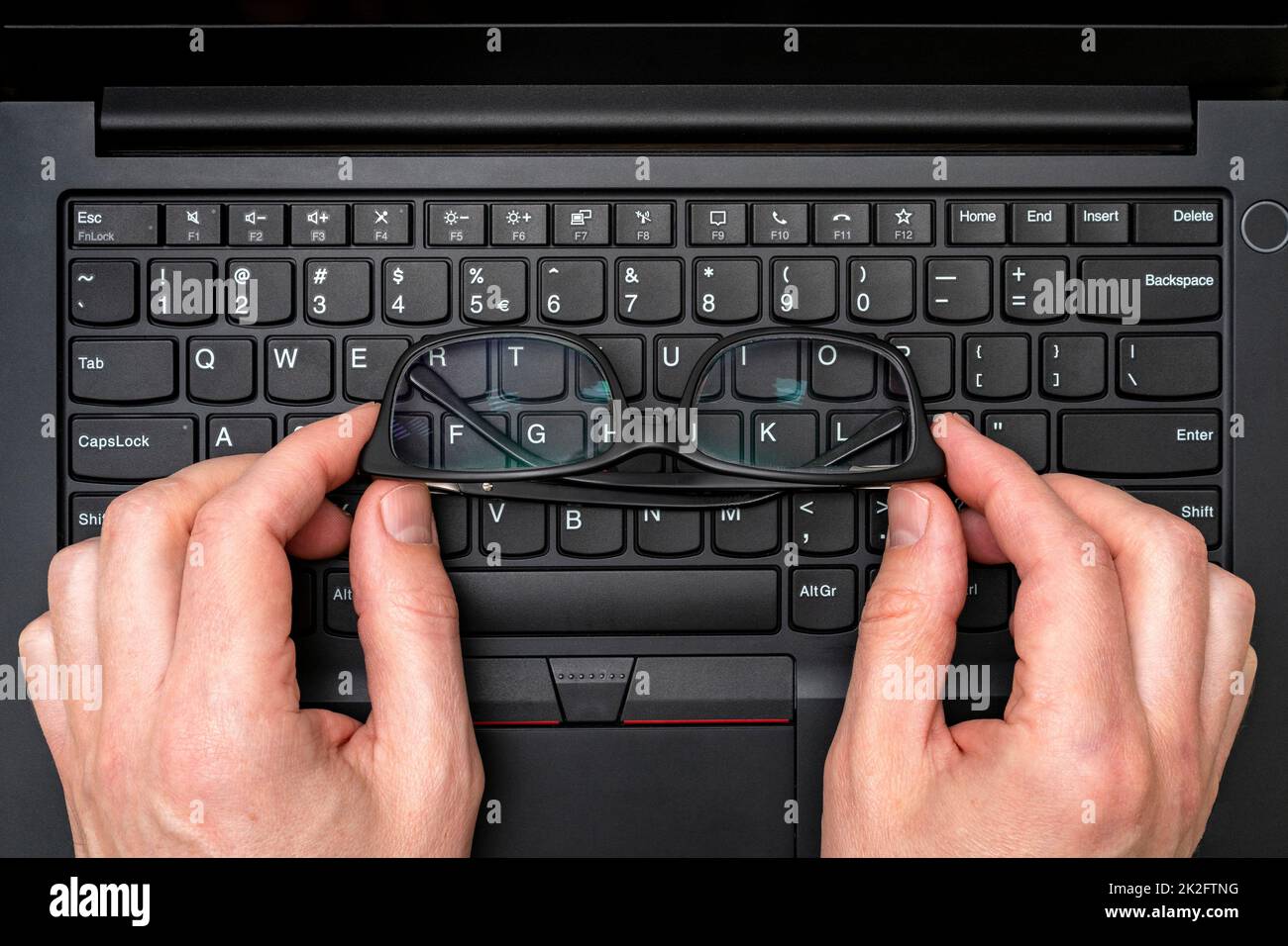 Hände, die die Brille auf der Laptop-Tastatur halten Stockfoto