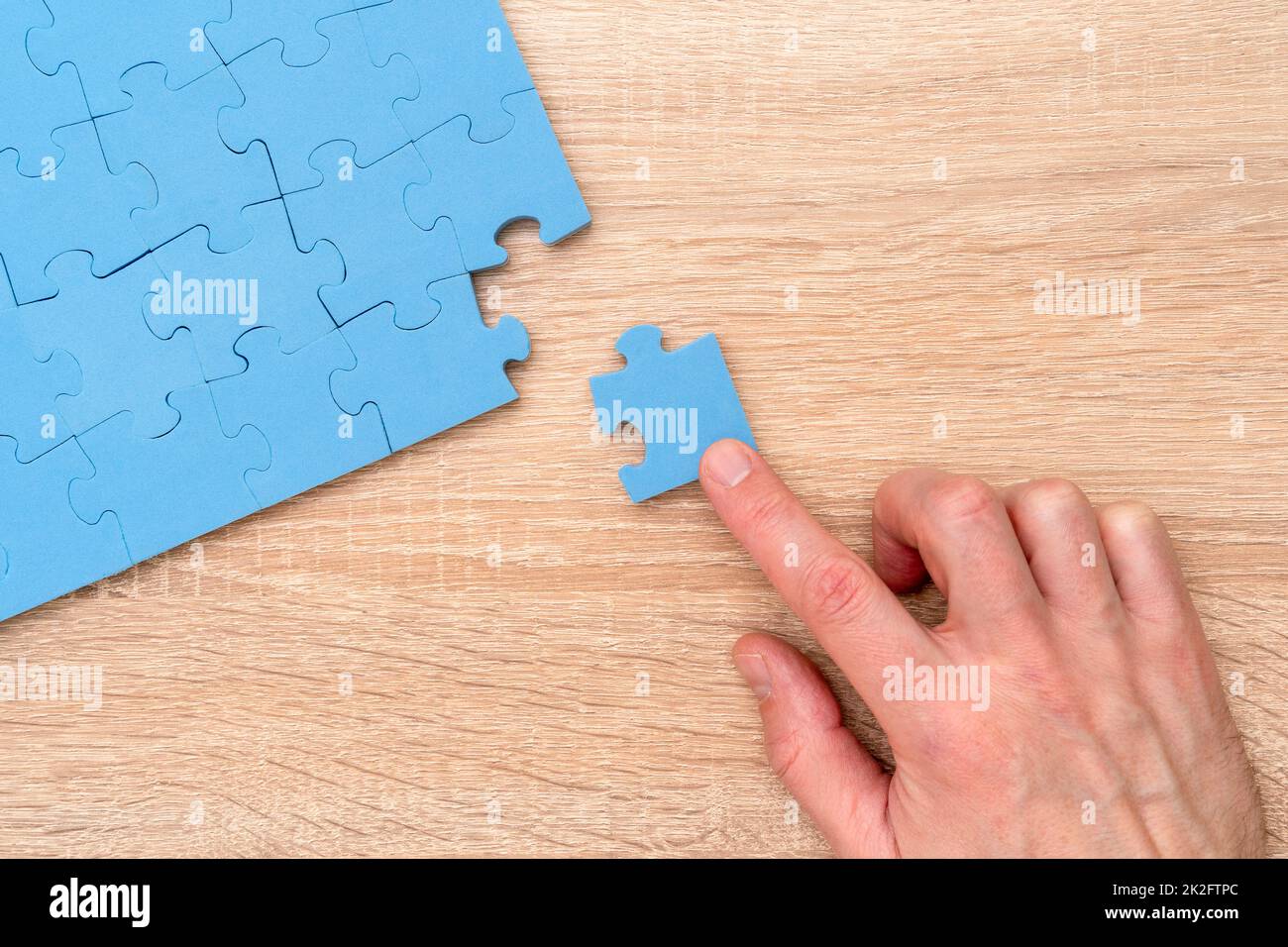 Die Hand schließt das Puzzle mit dem letzten Teil Stockfoto