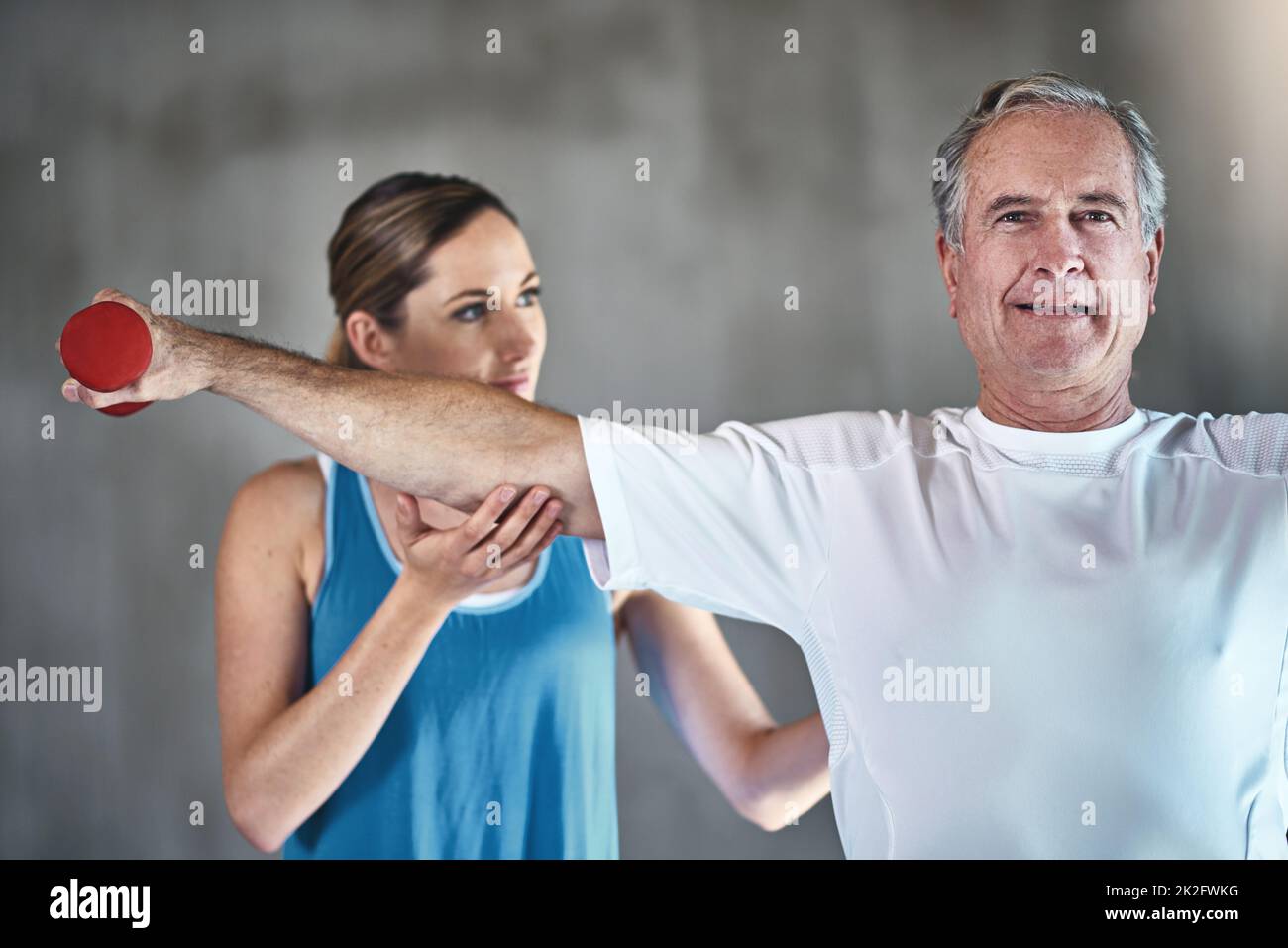 Zeit, aktiv am Leben teilzuhaben. Aufnahme eines älteren Mannes mit Gewichten mit Hilfe eines Physiotherapeuten. Stockfoto