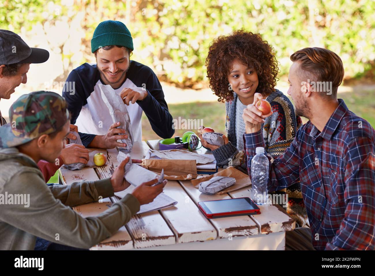 Gute soziale Stimmung auf dem Campus. Eine Gruppe von Freunden um einen Tisch im Freien. Stockfoto