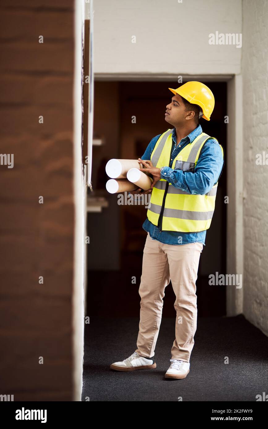 Bereit, dieses Projekt in die Rollen zu bringen. Aufnahme eines jungen Ingenieurs, der etwas an einer Wand liest. Stockfoto