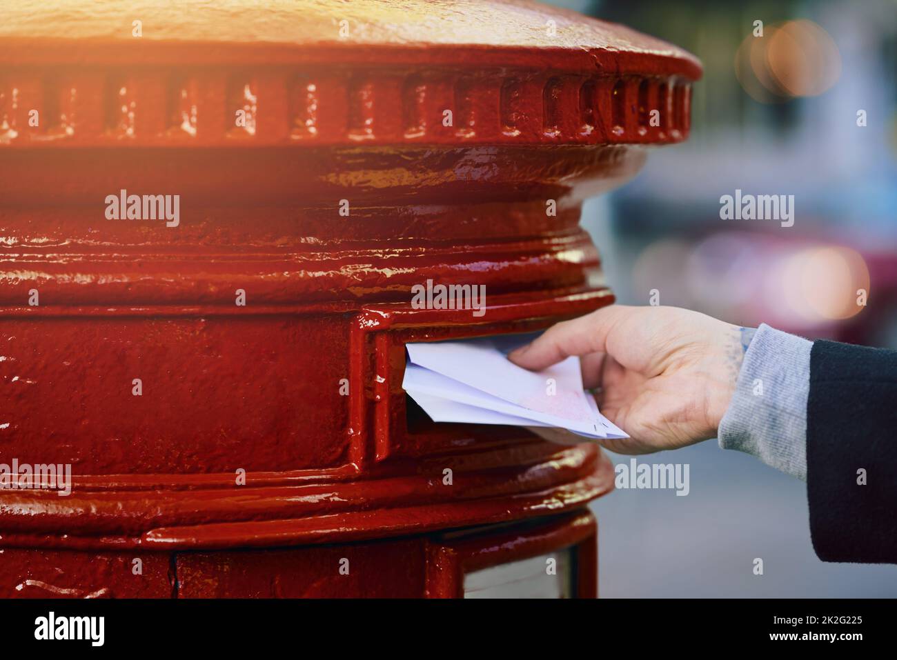 Vermitteln Sie Ihre Botschaft auf die alte Art und Weise. Ausgeschnittene Aufnahme eines Mannes, der Post in einen Briefkasten in der Stadt postete. Stockfoto