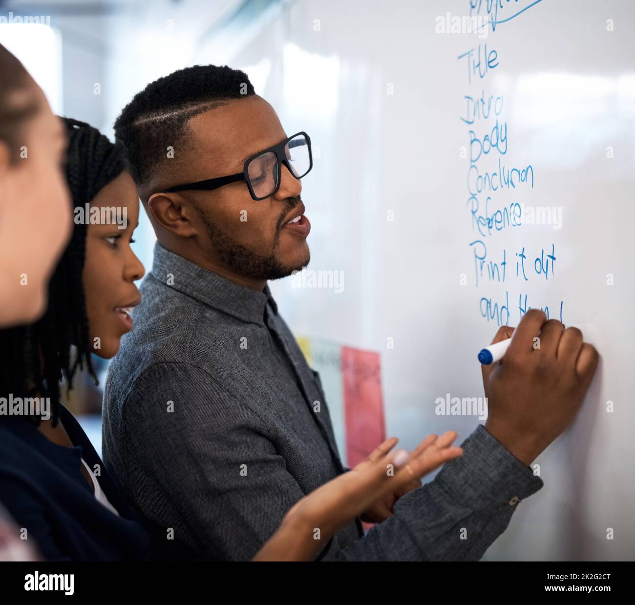 Ideen für das Projekt zu vertötend. Aufnahme einer Gruppe von Studenten beim Brainstorming an einem Whiteboard in der Klasse. Stockfoto