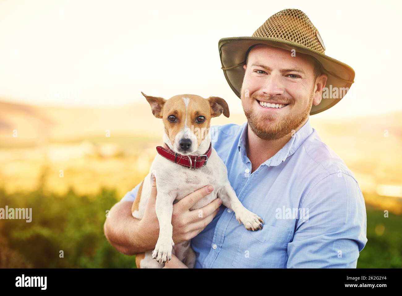 Herren bester Freund kann auch Herren bester Mitarbeiter sein. Aufnahme eines glücklichen Bauern, der seinen Hund in der Hand hält. Stockfoto