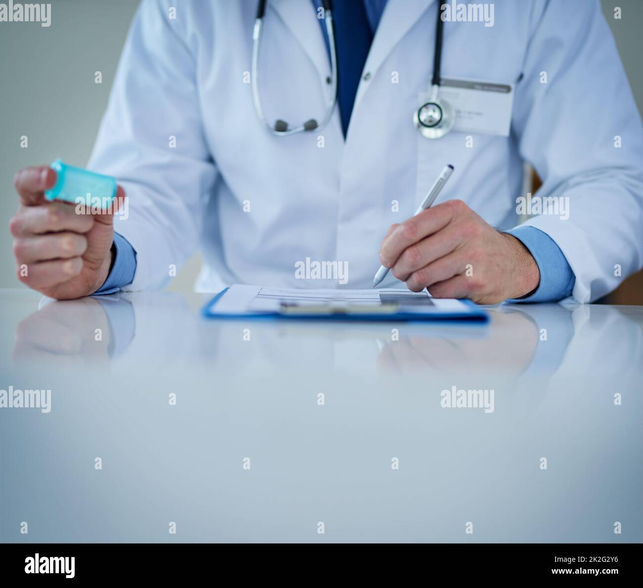 Verfolgen Sie Ihre Gesundheit. Nahaufnahme eines nicht erkennbaren Arztes, der Notizen schreibt, während er eine Flasche Medikamente in der Hand hält. Stockfoto