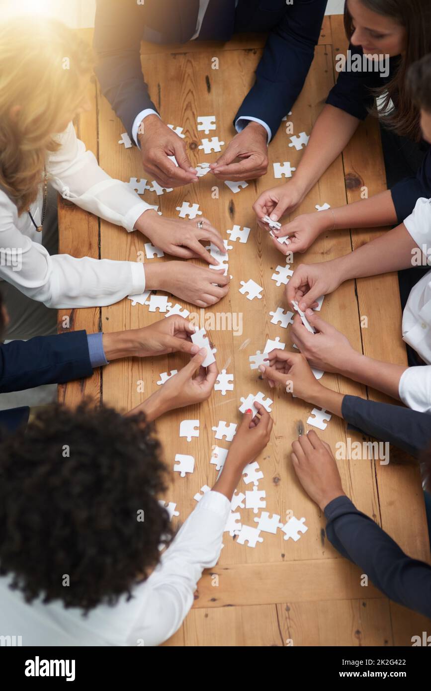 Lösungen Stück für Stück finden. Eine Aufnahme einer Gruppe von Geschäftsleuten, die in einem Büro ein Puzzle zusammenbauen. Stockfoto