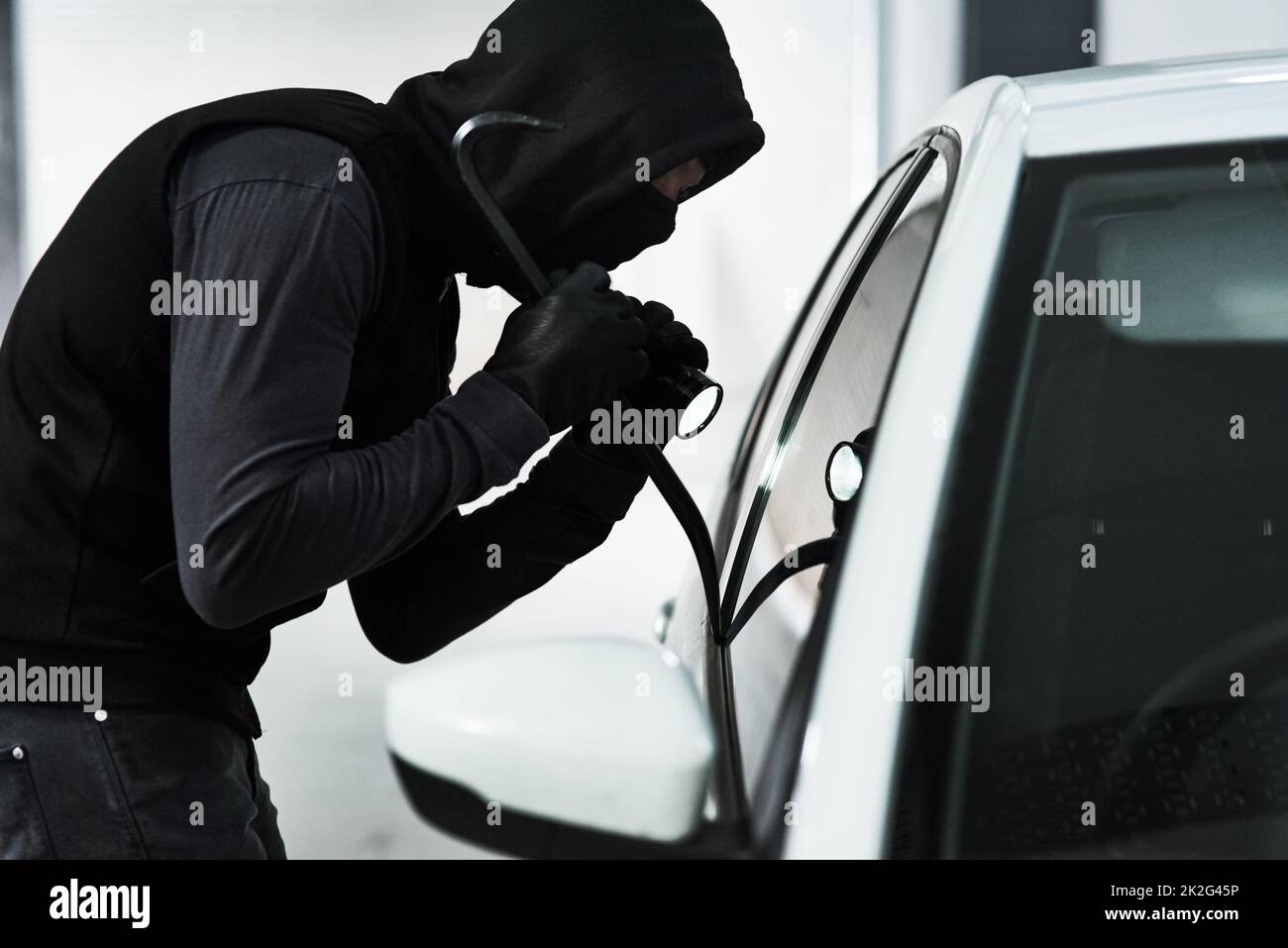 HES kennt keine Grenzen. Schuss eines maskierten Mannes, der mit einer Stahlwaffe in ein Auto auf einem Parkplatz einbrach. Stockfoto