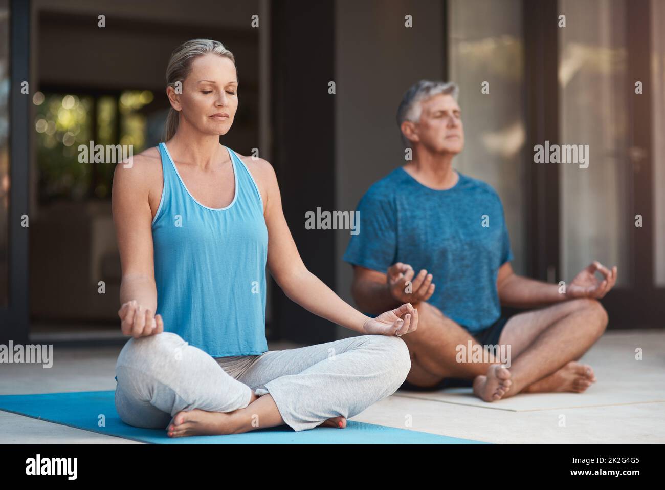 Frieden kommt in sich. Aufnahme eines reifen Paares, das sich ruhig mit gekreuzten Beinen in eine Yoga-Pose einstellt. Stockfoto
