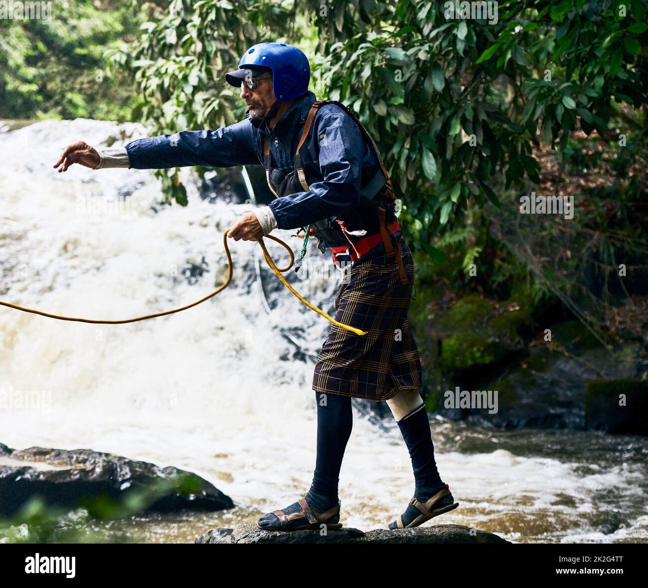 Halt dich am Seil fest. Aufnahme eines fokussierten Mannes mittleren Alters, der während des Tages eine Schutzausrüstung trägt, während er ein Seil an jemanden im Fluss draußen wirft. Stockfoto